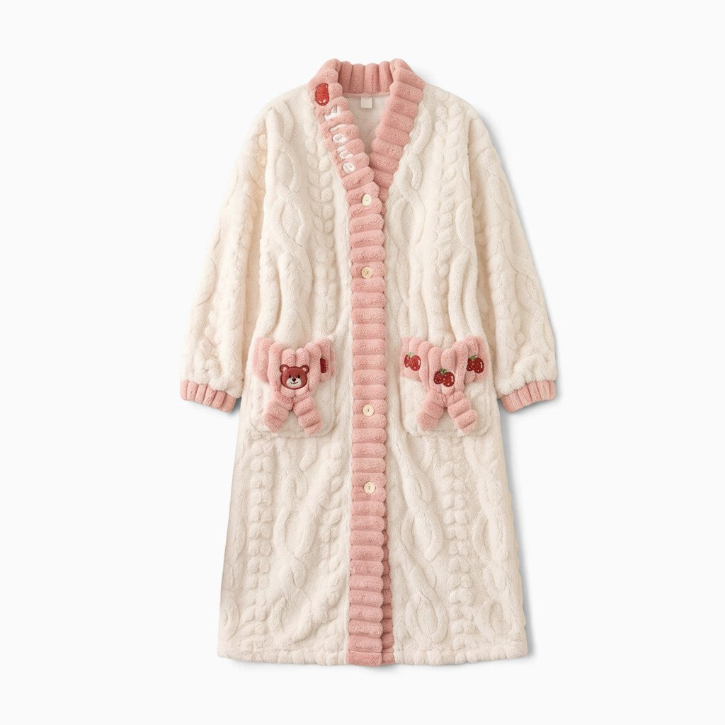Peignoir polaire UnPeignoir blanc cassé et rose avec poches décorées d'un ours et de fraises, texture torsadée douce.