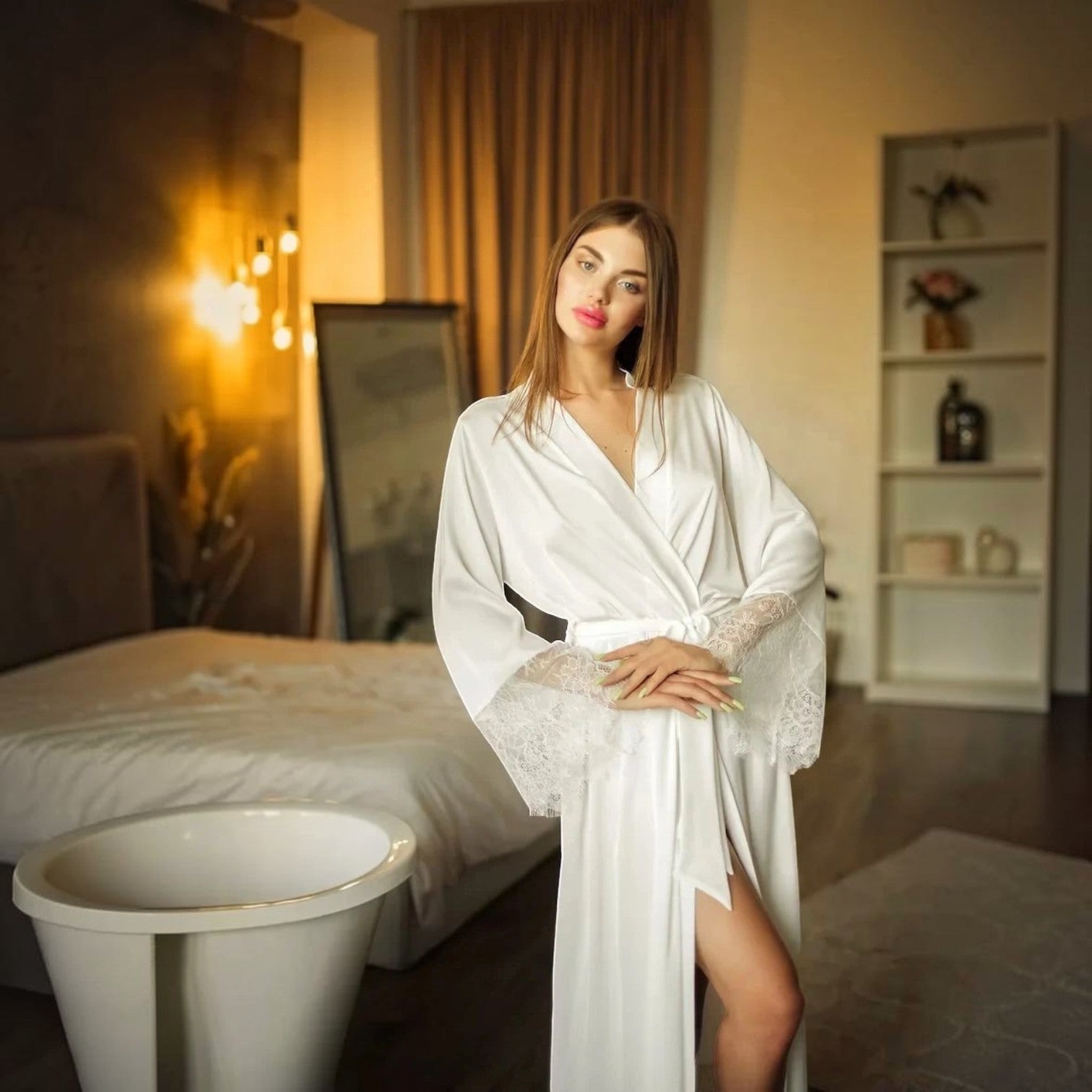 Femme portant un peignoir satin UnPeignoir blanc chic avec des détails en dentelle aux manches dans une chambre